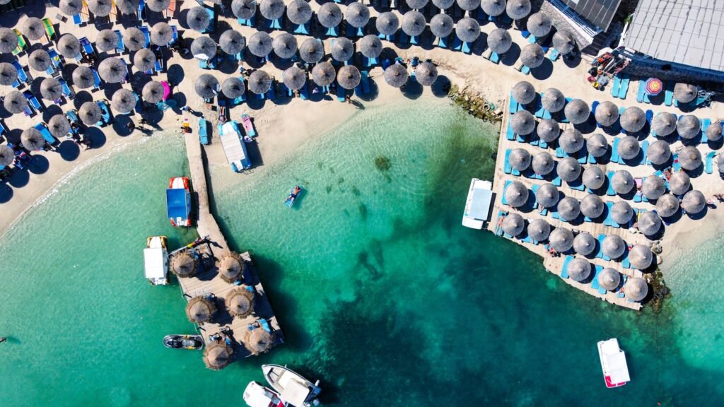 Türkisblaues Wasser und Sonnenschirme am Strand von Ksamil aus der Luft